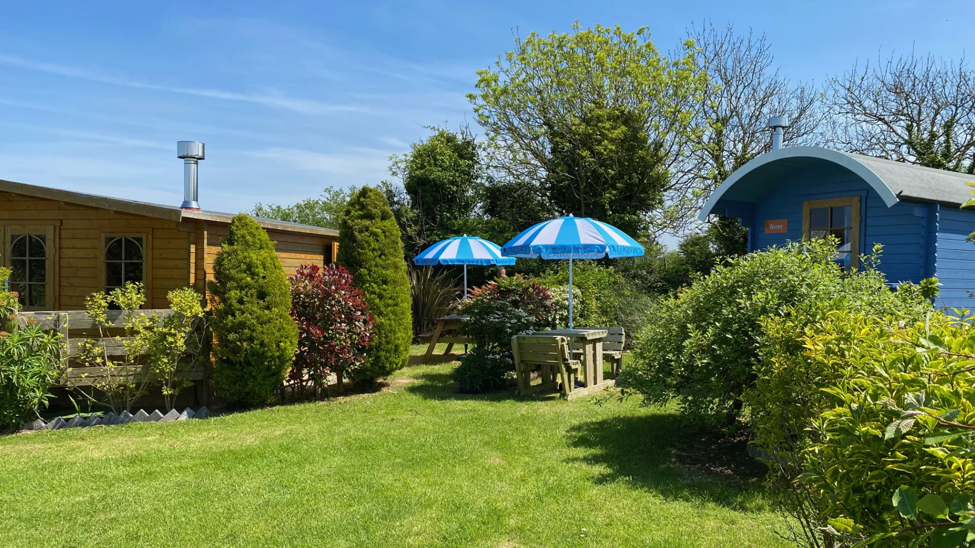 Each accommodation has a private garden and outdoor dining area. Here we see Harbour Glamping Cabin and Waves Shepherd's Hut with their outdoor dining areas.